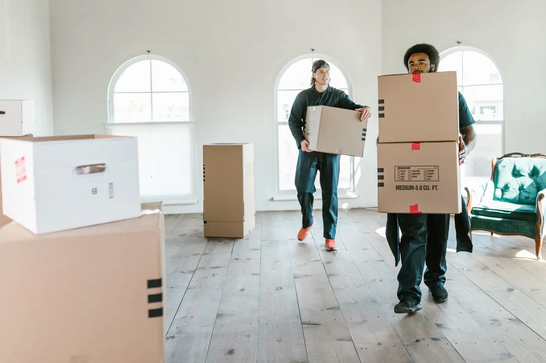 Umzugshelfer übergibt einem Kunden einen gepackten Umzugskarton